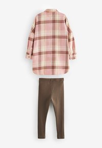 Rutig flanellskjorta i rosa med kräm- och brunaccenter, tillsammans med bruna ribbade leggings. Båda plagg har mjuka texturer och en avslappnad passform.