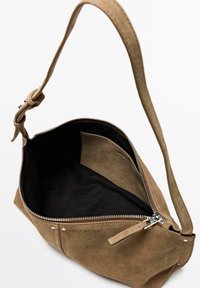 Sac à bandoulière en daim marron avec bandoulière réglable, fermeture éclair ouverte révélant un intérieur en tissu noir et une poche intérieure.