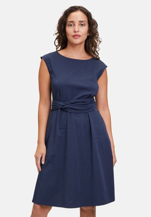 Navy-blaues Kleid mit kurzen Ärmeln, einem Twist-Detail an der Taille und einem ausgestellten Rock, aus glattem, weichem Stoff. Keine sichtbaren Muster oder Akzente.