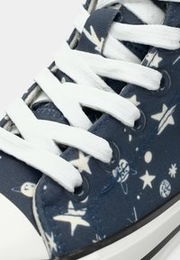 Μπλε πάνινο αθλητικό παπούτσι με λευκά κορδόνια και κρίκους, με εκτύπωση αστεριού και πλανήτη. Λαστιχένια σόλα και αντίθετη μαύρη λεπτομέρεια στο μπροστινό μέρος.