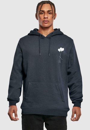 Dunkelblaue Kapuzenjacke mit strukturierter Oberfläche, ausgestattet mit einer Fronttasche und einer Illustration einer Figur, die zwei Ballons auf der linken Brusthälfte hält.