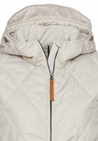 Gequilted lichtbeige jas met een afneembare capuchon, volle rits en een bruine leren accent op de ritstrekkker. Geweven stofoppervlak.