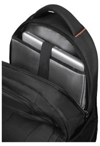 Zaino nero con scomparto imbottito per un laptop argentato. Presenta una chiusura con cerniera, maniglia superiore e un rivestimento interno lucido e liscio.