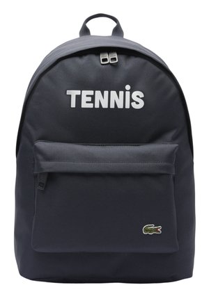 Sac à dos bleu marine avec poche avant zippée, texte "TENNIS" en haut, et petit logo de crocodile vert en bas à droite.