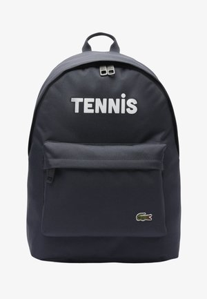 Marineblauer Rucksack mit Reißverschlusstasche vorne, dem Schriftzug "TENNIS" oben und einem kleinen grünen Krokodil-Logo unten rechts.