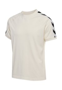 T-shirt à manches courtes en coton écru, présentant des motifs en chevrons noirs sur les épaules et un col rond.