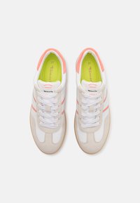 Sneaker bianchi e beige presentano una tomaia in pelle liscia con dettagli in suede, strisce arancioni e una soletta verde lime, completate da lacci bianchi.