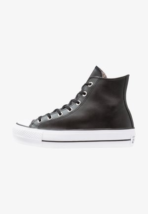 Black high-top sneaker made of leather with white rubber sole and toe cap. Features metallic eyelets and flat black laces. Textured accents.