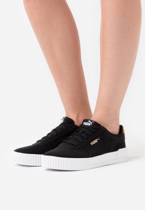 Sorte sneakers med en glat tekstur, hvid gummisål, gyldne detaljer og logo på siden og på tungen. Flade snørebånd fuldender designet.