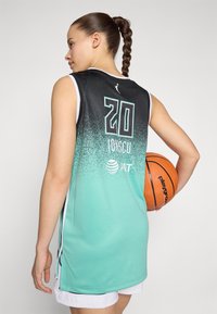 Maglia da basket con gradiente dal nero al teal, con il grande numero "20" e il nome "Ionescu" sulla schiena, texture a rete e accenti bianchi. Il giocatore tiene la palla.