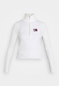 Pull à col roulé blanc côtelé avec une demi-fermeture éclair. Présente un petit logo rectangulaire Tommy Jeans sur la poitrine gauche. Manches longues.