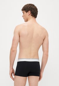 Melni bokseršorti no gludas auduma, ar baltu jostasvietu un melnu svītru. Dizains ir piegulošs ar nevainojamu apdari.