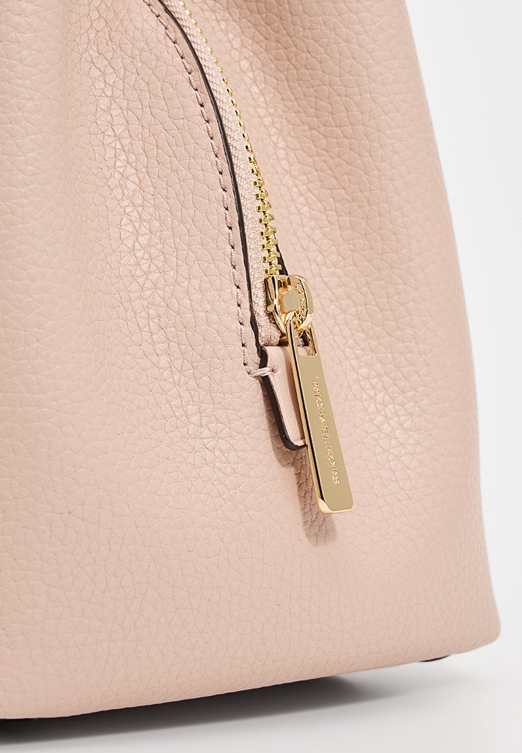 Lichtroze leren handtas met een gestructureerde afwerking. Voorzien van een gouden rits en hardware, met een minimalistisch design.