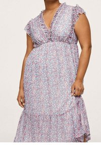 Kukkamekko, jossa on röyhelökaula-aukko ja hihat, joissa on vaaleanpunaisia, sinisiä ja valkoisia kuvioita, kerroksellinen helma ja läpikuultava kangastekstuuri.