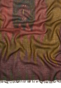 Miękka tkana tkanina z wielokolorowym wzorem plemiennym w ziemistych odcieniach, z frędzlami na brzegach oraz widoczną teksturą z delikatnymi fałdami.