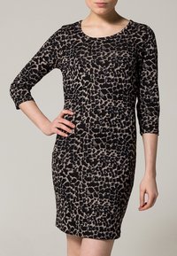 Leopardmönstrad klänning med 3/4 ärmar, rund halsringning, figurnära passform, tillverkad av mjukt tyg i svarta och beiga nyanser.
