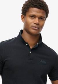 Marine polo shirt met een knoopsluiting bij de kraag, gestructureerde stof, korte mouwen en een geborduurd logo op de borst.
