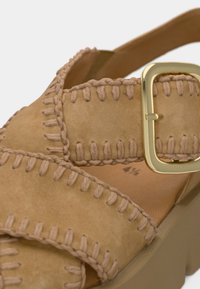 Μπεζ δερμάτινο σανδάλι με σχέδιο υφασμένης ραφής, φαρδιά λωρίδα με χρυσή αγκράφα και παχύ, υφασμένο πέλμα.