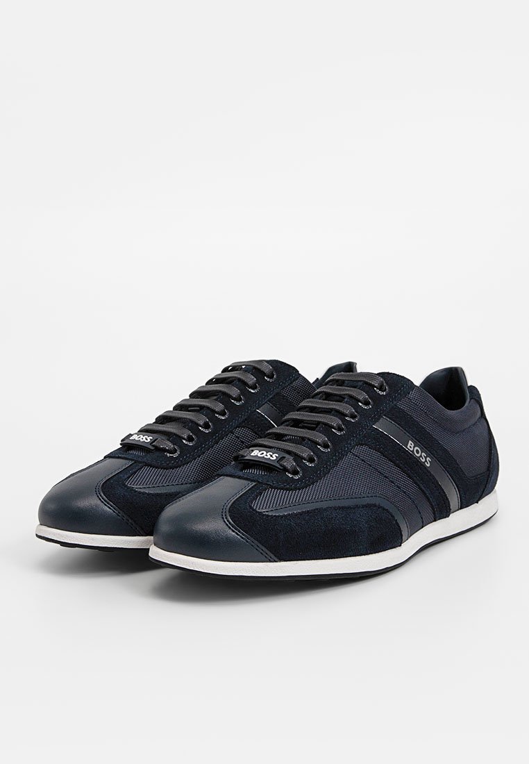 Baskets bleu foncé en cuir lisse et maille texturée, avec une semelle blanche contrastante et un logo de la marque sur la languette.