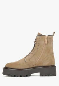 Beżowe zamszowe botki za kostkę, z przodem na sznurówki, bocznym zamkiem, detalami w stylu brogue oraz masywną czarną podeszwą z gumy z rowkami dla lepszej przyczepności.