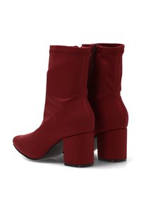 Botines rojos de tobillo hechos de tela suave, con punta afilada y tacón cuadrado. La parte trasera tiene una cremallera para facilitar el calzado.