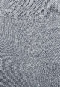 Graue Socken aus weichem, strukturiertem Stoff, mit einem glatten Strickmuster und einem gerippten Bündchen oben für einen bequemen Sitz.