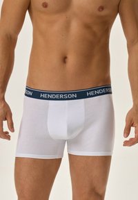 Białe bokserki wykonane z bawełny z ciemnoniebieskim pasem w talii z napisem "HENDERSON". Charakteryzują się dopasowanym krojem i gładką strukturą.