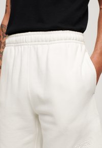Superdry & Co EMBOSSED - Pantalon de survêtement - new chalk white