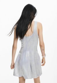 Hõbedane kleit, millel on vormitud ülakeha ja lehviva lõikega seelik. Valmistatud siledast, peegeldavast kangast, millel on sügav kaelaosa tagaosa ning peen tekstuuriline muster.