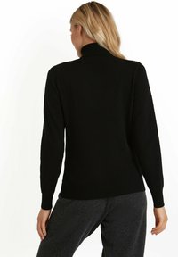 Czarny sweter dzianinowy z wysokim kołnierzem, długimi rękawami, ściągaczami na mankietach i dole, o gładkiej fakturze. Odpowiedni na codzienne noszenie.