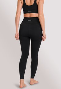 Black sports bra and high-waisted leggings set, featuring textured fabric, fitted design, and ribbed accents at the waistbands.