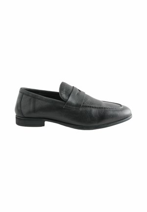 Black leather slip-on loafer with a low heel and a stitched strap detail across the top, shown from the side on a white background.