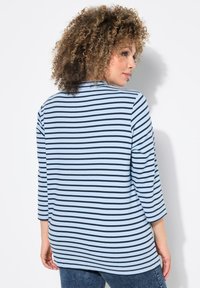 Blå och vit randig långärmad topp med rundad halsringning och lätt rundad nederkant, tillverkad av ett mjukt, flexibelt tyg.