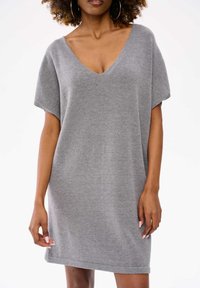 Szara, oversize sukienka wykonana z miękkiego, dzianinowego materiału. Posiada głęboki dekolt w kształcie litery V i krótkie rękawy. Prosty fason bez widocznych wzorów czy akcentów.
