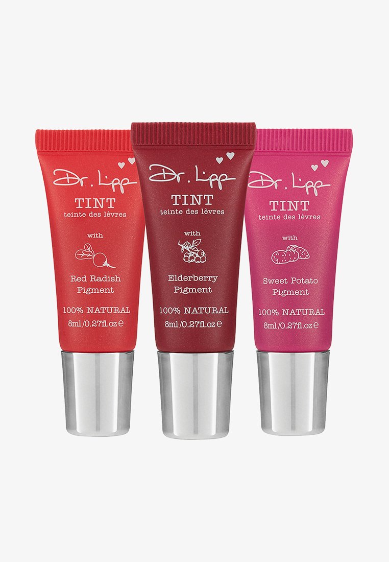 Trois tubes de teinte à lèvres avec des bouchons en argent. De gauche à droite : rouge, rouge foncé et rose, étiquetés avec des pigments naturels et le nom de la marque.
