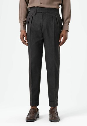 Donkergrijze geplooide broek met een nauwsluitende pasvorm, voorzien van zijzakken en een decoratieve ceintuurlus. Gladde textuur met opgerolde zomen.