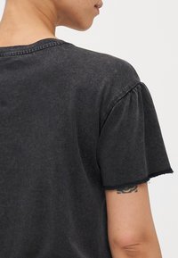 Grijze t-shirt met korte mouwen, van een zachte stof, met rafelige mouwranden en een relaxte pasvorm. Zichtbare achternaad en lichte puff in de mouwen.