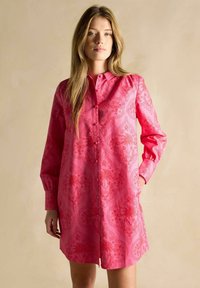 Rosa Hemdkleid mit knöpfbarem Frontverschluss, langen Ärmeln und Paisley-Muster. Aus glattem Stoff mit seitlichen Taschen gefertigt.