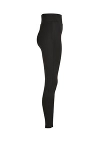 Leggings noirs en tissu extensible, taille haute, design ajusté, texture lisse et longueur cheville sans coutures visibles.