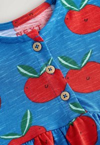 Robe en coton bleue avec des motifs de pommes rouges et de feuilles vertes, avec un col rond, des détails en boutons en bois et une jupe froncée.