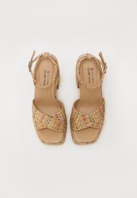 Tan vegan sandals with woven upper featuring colorful accents. Open toe design with ankle strap and square heel. Smooth interior material.