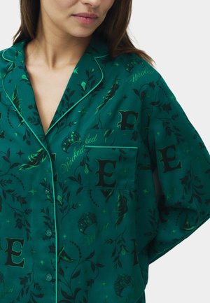 Camisa de pijama verde con patrón de flores y plumas, con elementos de texto en negro, bolsillo en el pecho y ribete verde en el cuello.
