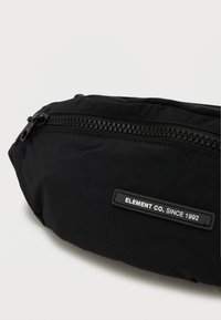 Marsupio nero realizzato in nylon con una texture liscia, dotato di una cerniera superiore e un'etichetta con la scritta "ELEMENT CO. SINCE 1992."