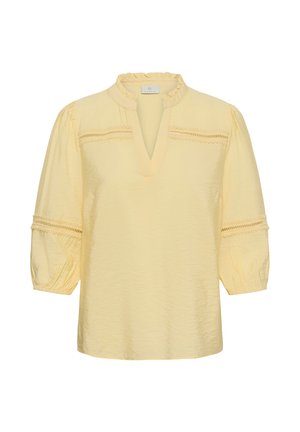 Blouse jaune clair avec col à volants, encolure en V, manches trois-quarts bouffantes, et détails en dentelle sur la poitrine et les manches.