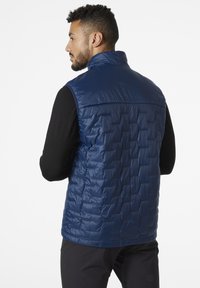 Chaleco aislante azul marino con un diseño acolchado, cuello alto y una textura lisa y brillante. Presenta una silueta ajustada y un material ligero.
