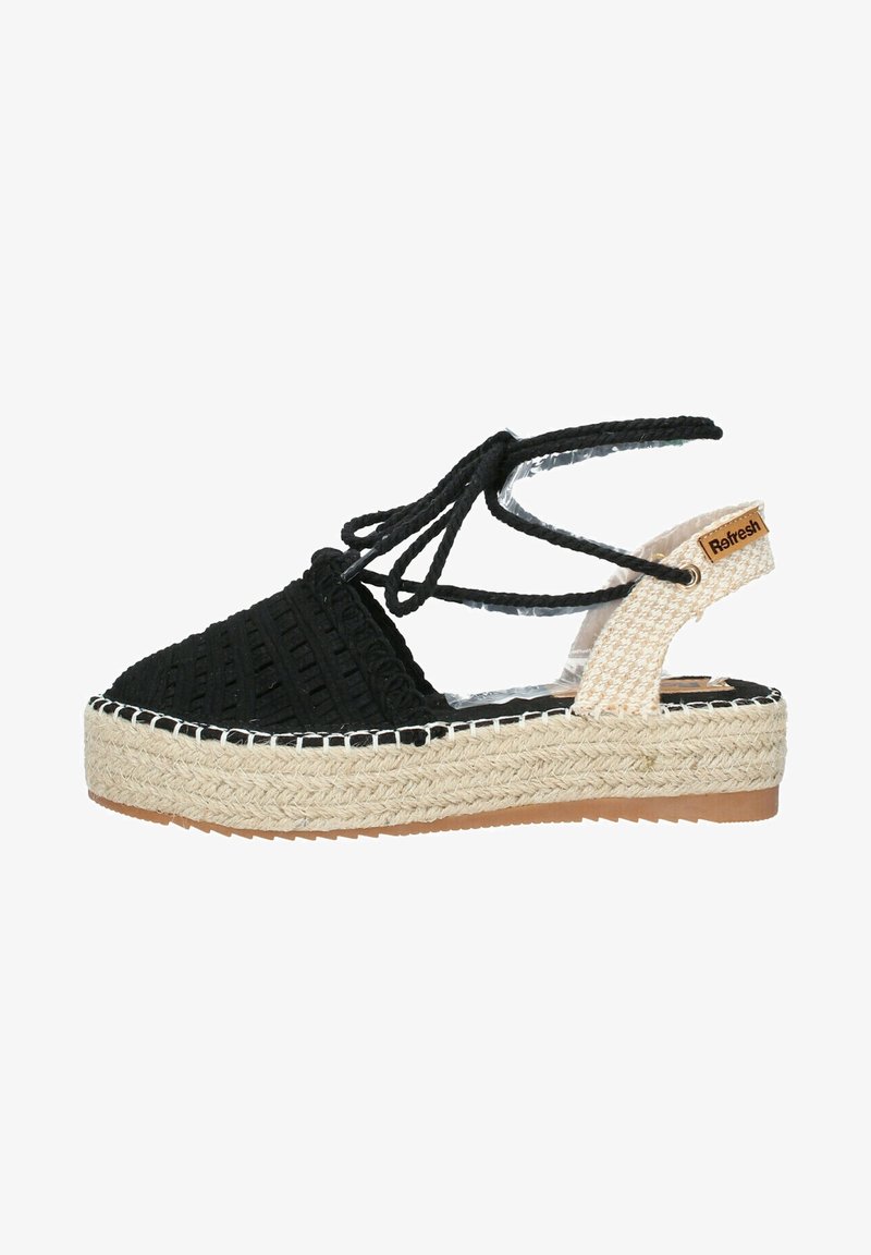 Sandale espadrille tissée noire avec un design à lacets, plateforme en jute et accents beiges. Présente un bord blanc cousu et une étiquette de marque.