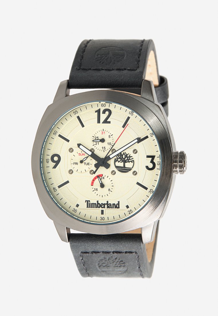 Reloj redondo con caja metálica en tono plateado, esfera color crema, marcadores de horas negros, función de fecha y día, montado en una correa de cuero negra con logo.