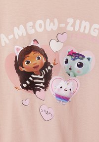 Hellrosa T-Shirt mit einem Cartoon-Mädchen, das lockiges Haar hat und Katzenohren trägt, einem schwarz-weißen gestreiften Shirt und zwei bunten Katzenfiguren in Herzen.