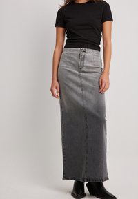 Camiseta negra combinada con una falda de mezclilla gris de tiro alto y longitud hasta el tobillo, con un acabado desgastado y detalles de costuras visibles.