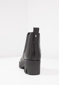 Botas de tobillo de cuero negro con un acabado suave, paneles laterales elásticos, un tacón robusto y una tira en la parte posterior para facilitar su uso.